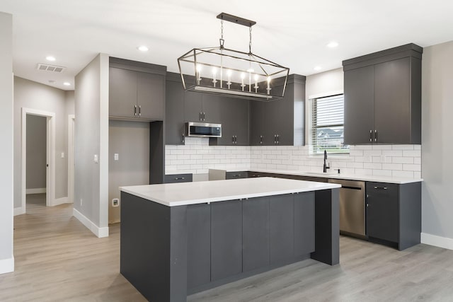 kitchen featuring pendant lighting, light wood-type flooring, stainless steel appliances, and a kitchen island