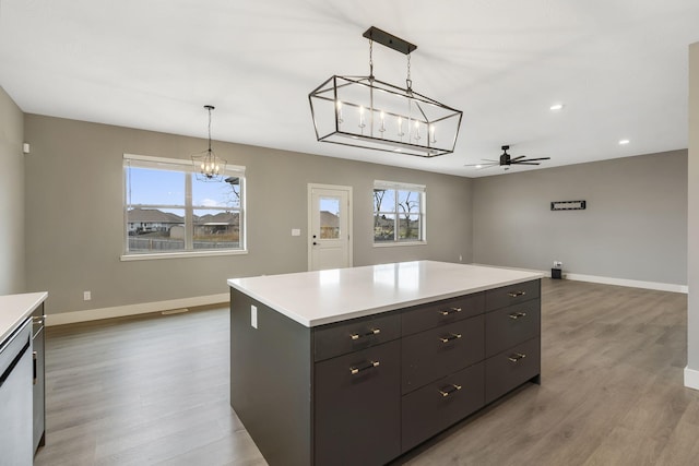 kitchen featuring ceiling fan with notable chandelier, a center island, light hardwood / wood-style floors, and plenty of natural light