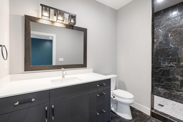 bathroom with tiled shower, vanity, and toilet