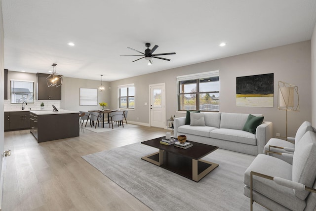 living room with ceiling fan with notable chandelier and light wood-type flooring