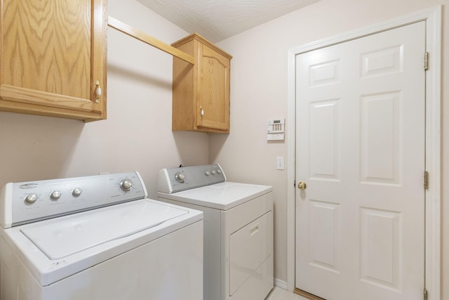 washroom with cabinets, a textured ceiling, and washing machine and dryer