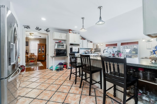 kitchen featuring appliances with stainless steel finishes, light wood-type flooring, ceiling fan, white cabinetry, and lofted ceiling