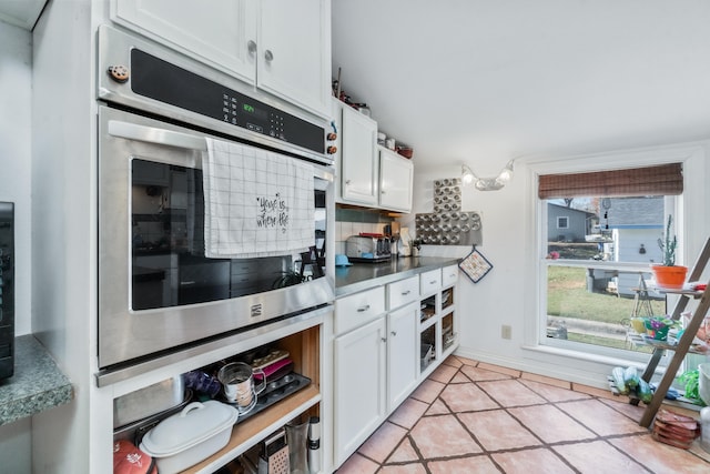 kitchen with white cabinets, light tile patterned floors, backsplash, and double oven