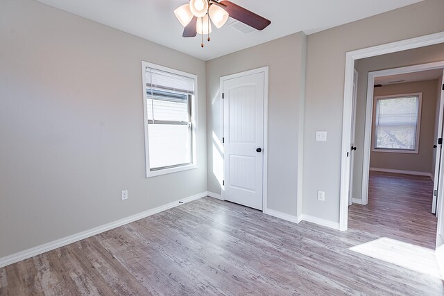 unfurnished bedroom featuring multiple windows, ceiling fan, and light hardwood / wood-style floors