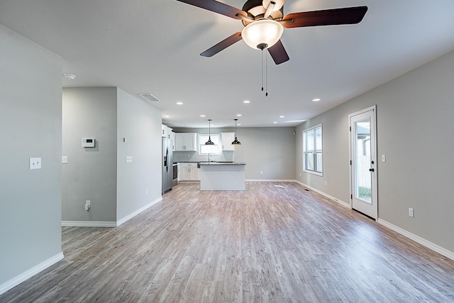 unfurnished living room with light hardwood / wood-style flooring, ceiling fan, and sink