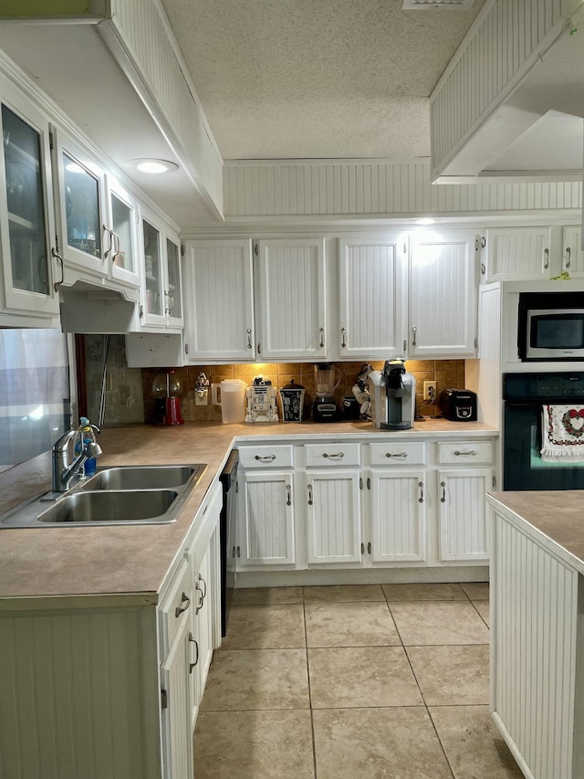 kitchen with black appliances, white cabinetry, sink, and light tile patterned floors