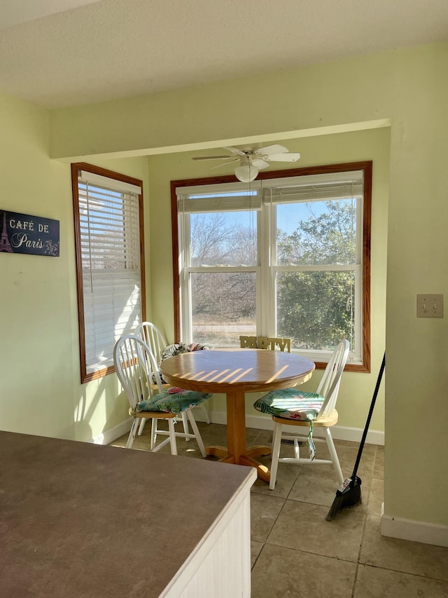 tiled dining space with plenty of natural light and ceiling fan