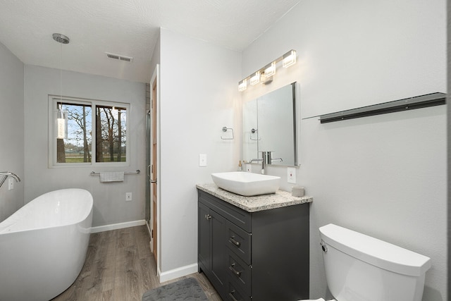 bathroom with a textured ceiling, toilet, a bathtub, vanity, and hardwood / wood-style flooring