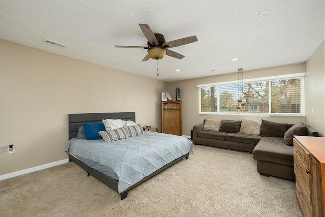 bedroom featuring light carpet, a textured ceiling, and ceiling fan