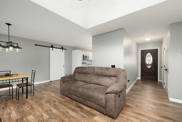 living room with a barn door, ceiling fan, and wood-type flooring