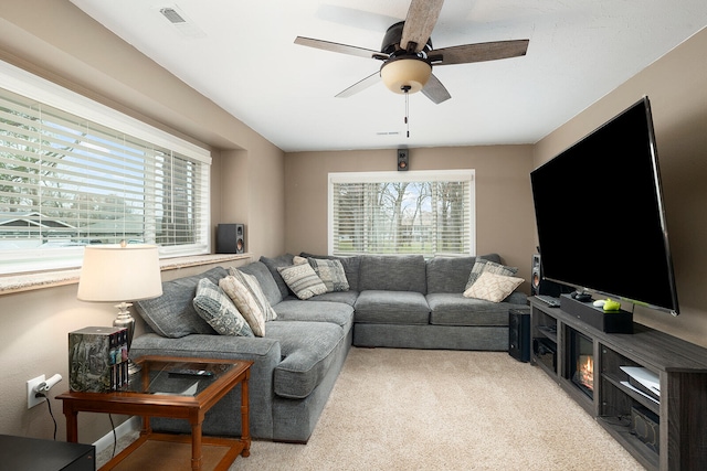 living room featuring ceiling fan, light colored carpet, and a healthy amount of sunlight