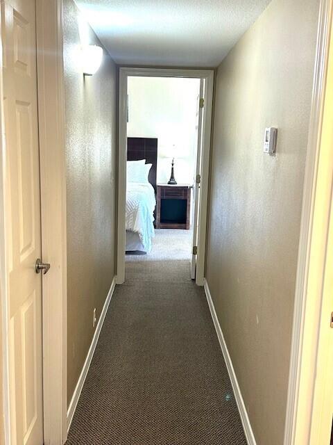 hall with carpet floors and a textured ceiling