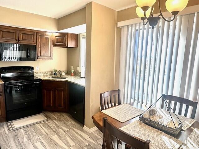 kitchen featuring sink, a chandelier, light hardwood / wood-style flooring, hanging light fixtures, and black appliances