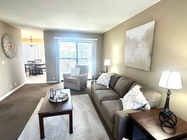 carpeted living room with an inviting chandelier