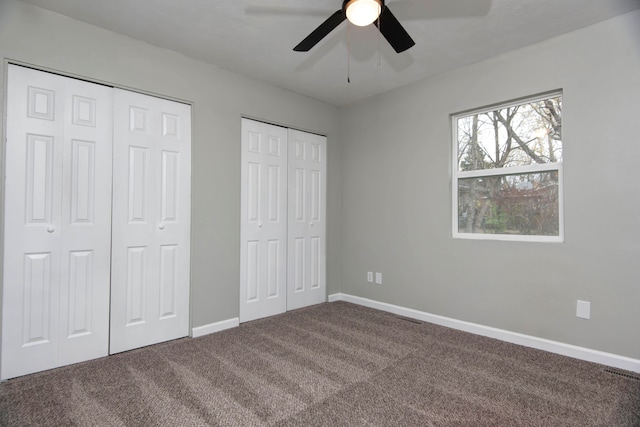 unfurnished bedroom with carpet floors, two closets, and ceiling fan