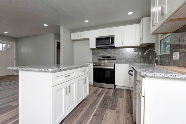 kitchen featuring appliances with stainless steel finishes, a kitchen island, white cabinetry, and dark wood-type flooring