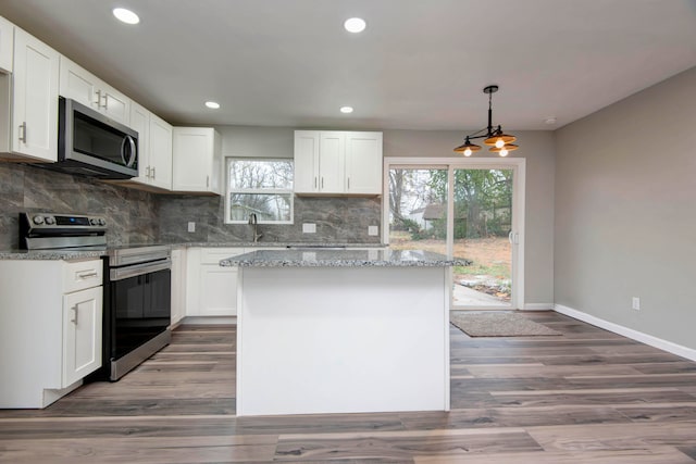 kitchen featuring a center island, white cabinets, hanging light fixtures, appliances with stainless steel finishes, and dark hardwood / wood-style flooring