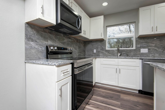 kitchen featuring decorative backsplash, light stone counters, stainless steel appliances, dark wood-type flooring, and white cabinets