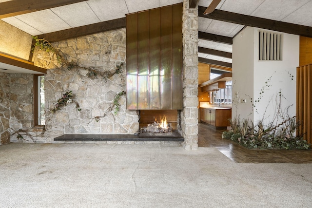 unfurnished living room featuring a fireplace, carpet, and lofted ceiling with beams