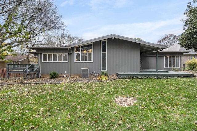 rear view of house featuring a lawn and a wooden deck