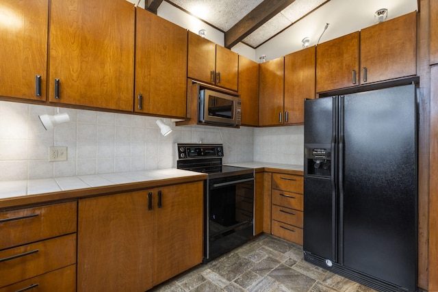 kitchen with backsplash, lofted ceiling with beams, tile counters, and black appliances