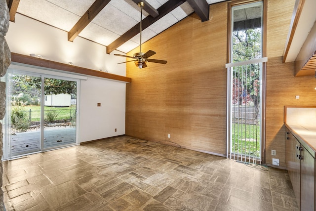 unfurnished living room featuring high vaulted ceiling, plenty of natural light, and wooden walls