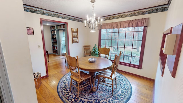 dining area featuring a chandelier, a textured ceiling, and light wood-type flooring