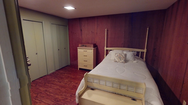 bedroom with wood walls and dark hardwood / wood-style flooring