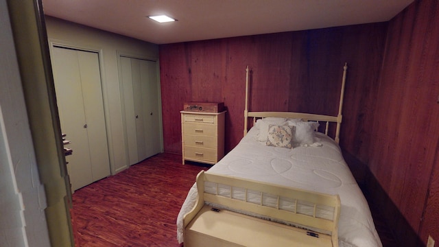 15047 E Peace Rd, Nevada, MO 64772 - bedroom with two closets, dark wood-style flooring, and wood walls