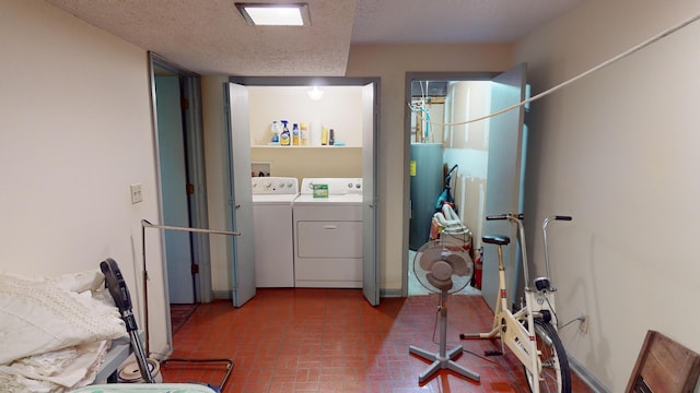 clothes washing area featuring washer and dryer, a textured ceiling, and water heater