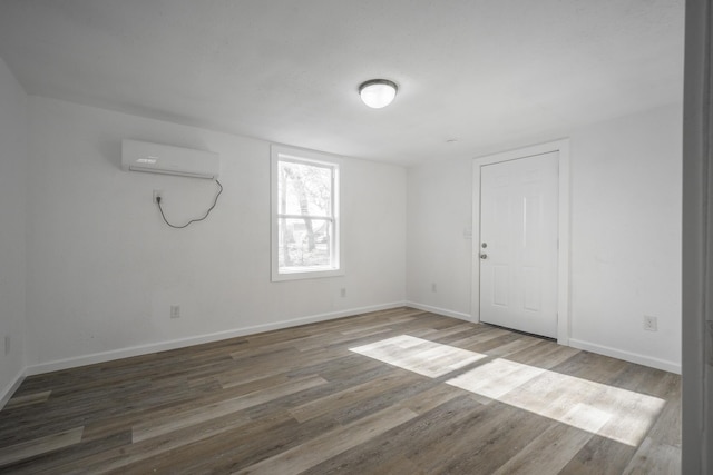 spare room with a wall mounted air conditioner and hardwood / wood-style floors