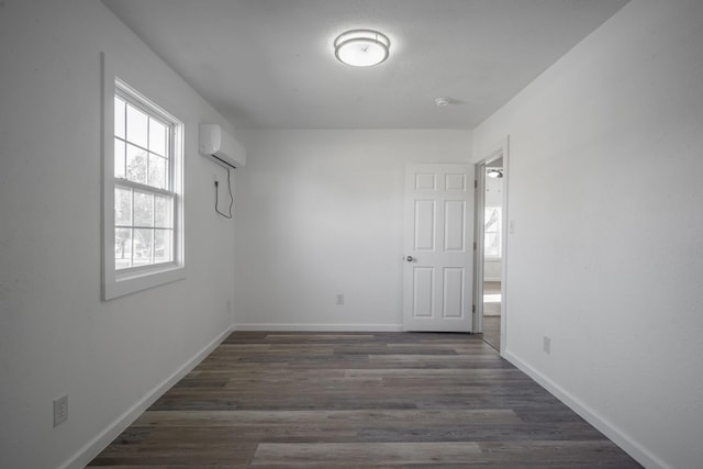 empty room with a wall mounted air conditioner and dark wood-type flooring