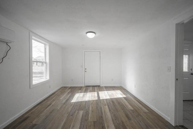 unfurnished room with wood-type flooring and a wall mounted air conditioner