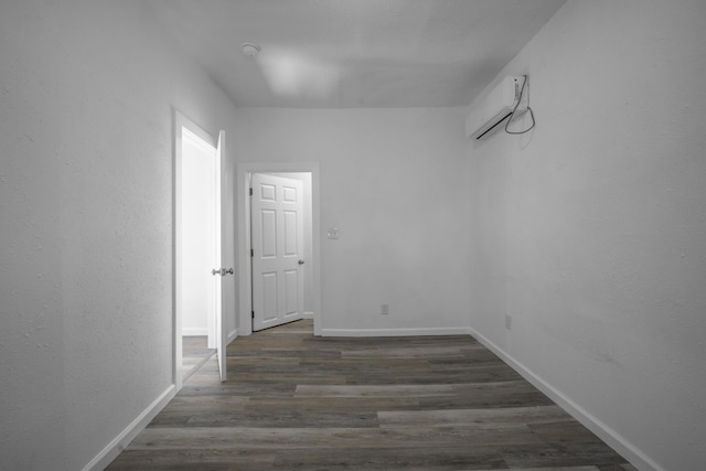 empty room with a wall unit AC and dark hardwood / wood-style flooring