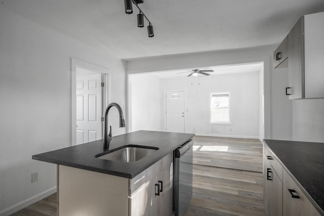 kitchen with ceiling fan, sink, dark hardwood / wood-style flooring, stainless steel dishwasher, and a center island with sink