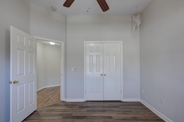 unfurnished bedroom with a closet, dark hardwood / wood-style floors, and ceiling fan