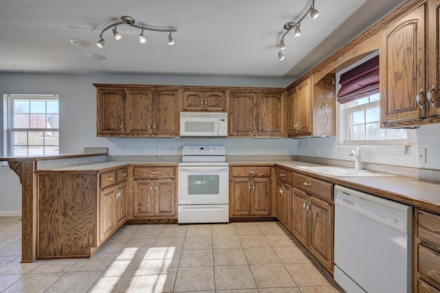 kitchen featuring kitchen peninsula, a wealth of natural light, sink, and white appliances