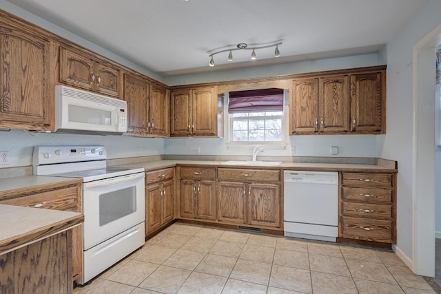 kitchen featuring white appliances, sink, and light tile patterned floors