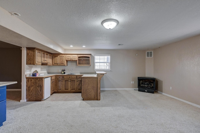 kitchen featuring a wood stove, light carpet, sink, and dishwasher