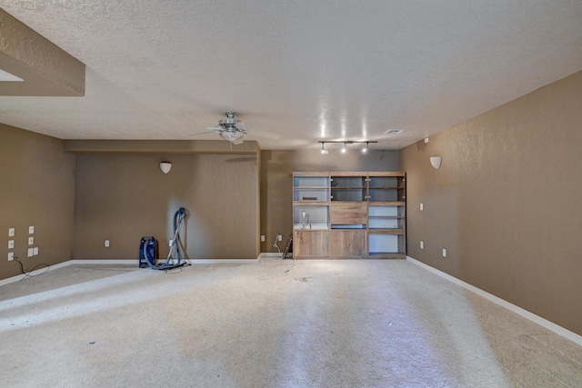 interior space with ceiling fan, rail lighting, and a textured ceiling