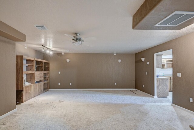 living room with track lighting, sink, ceiling fan, a textured ceiling, and light colored carpet