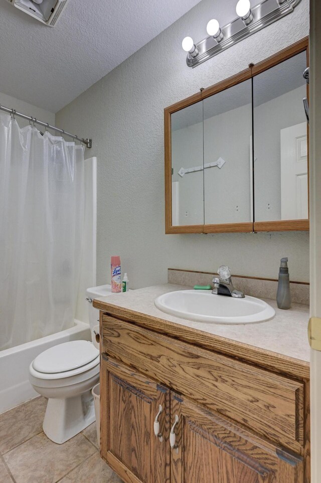 full bathroom featuring vanity, a textured ceiling, shower / bathtub combination with curtain, tile patterned flooring, and toilet