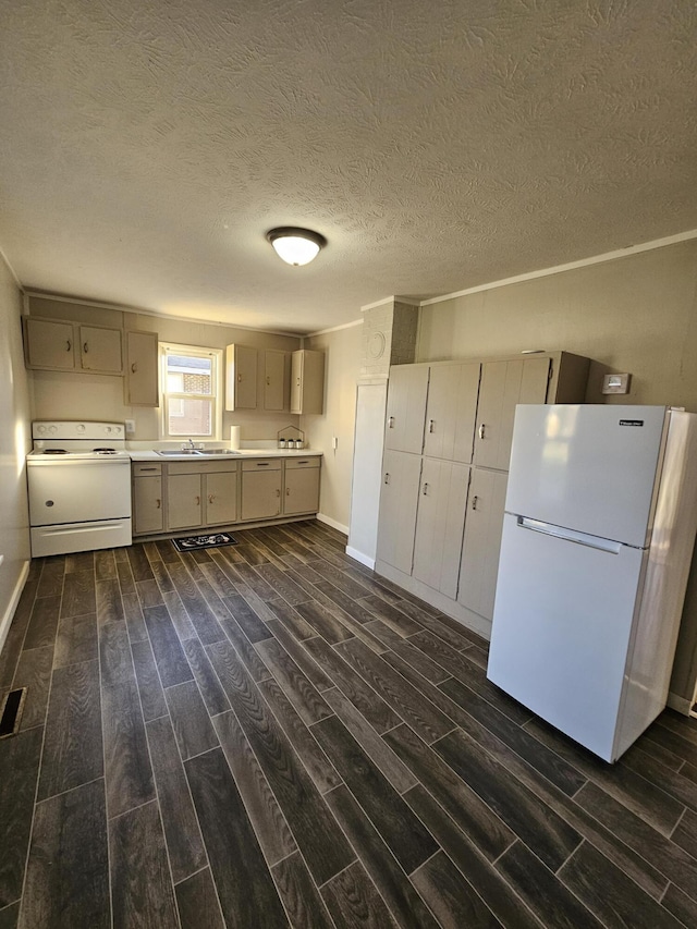 kitchen featuring dark hardwood / wood-style floors, sink, white appliances, and a textured ceiling