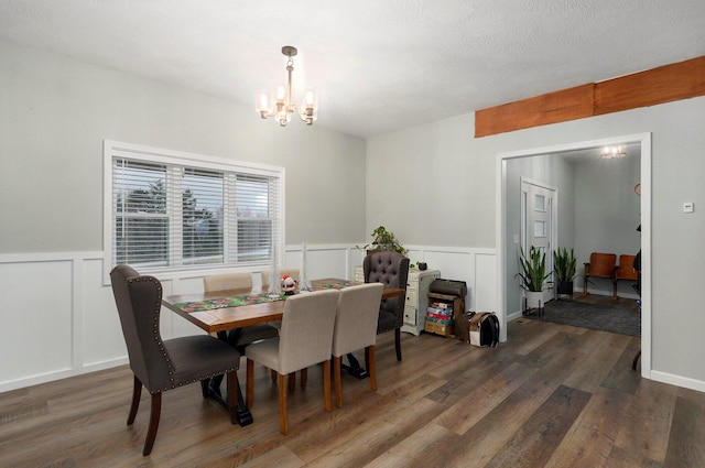 dining room featuring a textured ceiling, an inviting chandelier, and dark wood-type flooring