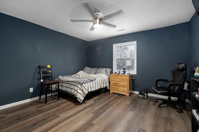 bedroom with a textured ceiling, dark hardwood / wood-style floors, and ceiling fan