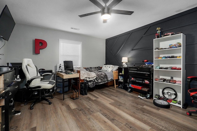 bedroom with ceiling fan, wood-type flooring, and a textured ceiling