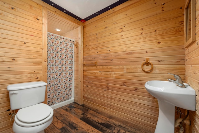 bathroom with hardwood / wood-style flooring, curtained shower, toilet, and wooden walls