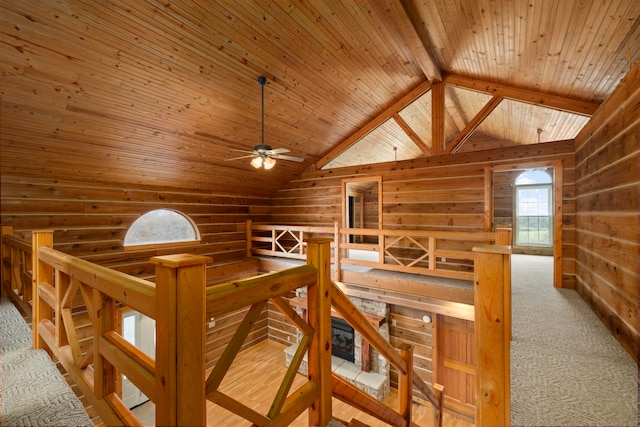 hallway with lofted ceiling with beams, light colored carpet, wood ceiling, and wooden walls