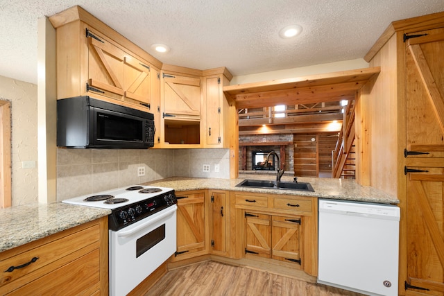 kitchen featuring light stone countertops, sink, light hardwood / wood-style floors, a textured ceiling, and white appliances