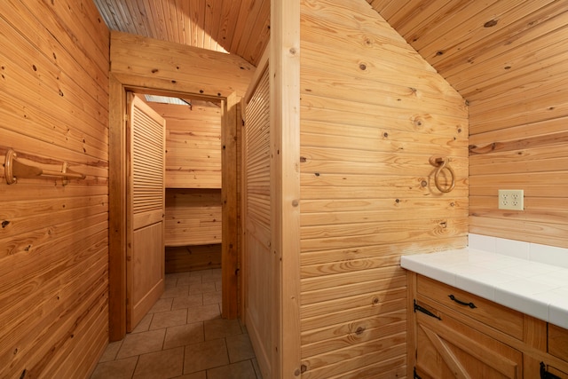 bathroom with tile patterned flooring, wood walls, wood ceiling, and vaulted ceiling